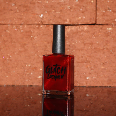 Stonewall by Glitch Lacquer, brick red jelly with bright red magnetic shimmer, bottle against a brick backdrop