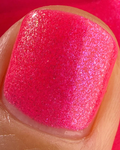 ACT UP by Glitch Lacquer, neon pink crelly with cool-toned pink sparkle, macro on medium skin tone