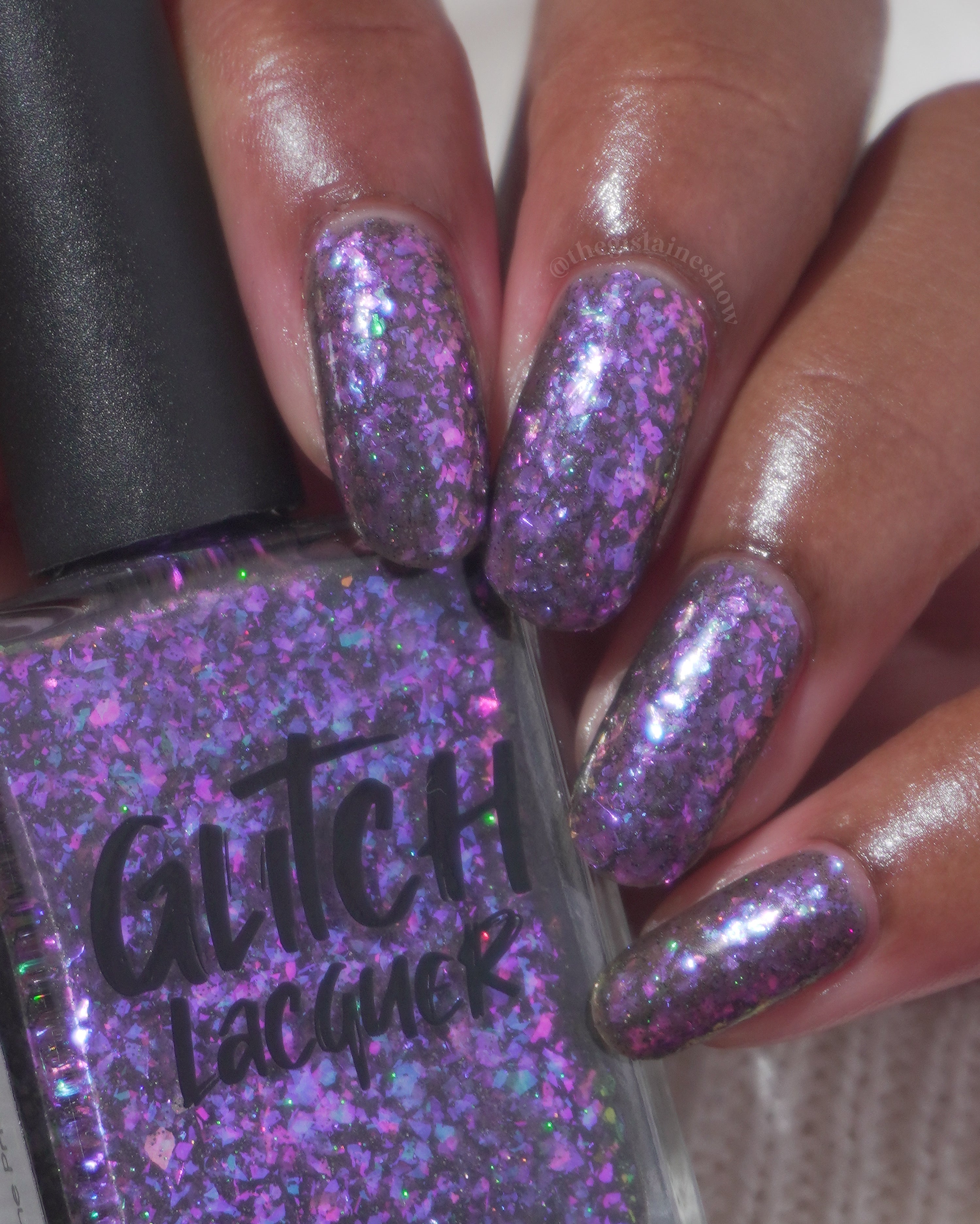 AVEN by Glitch Lacquer, soft black base, iridescent purple flakes, holo micro-glitter, on medium-deep skin tone square nails