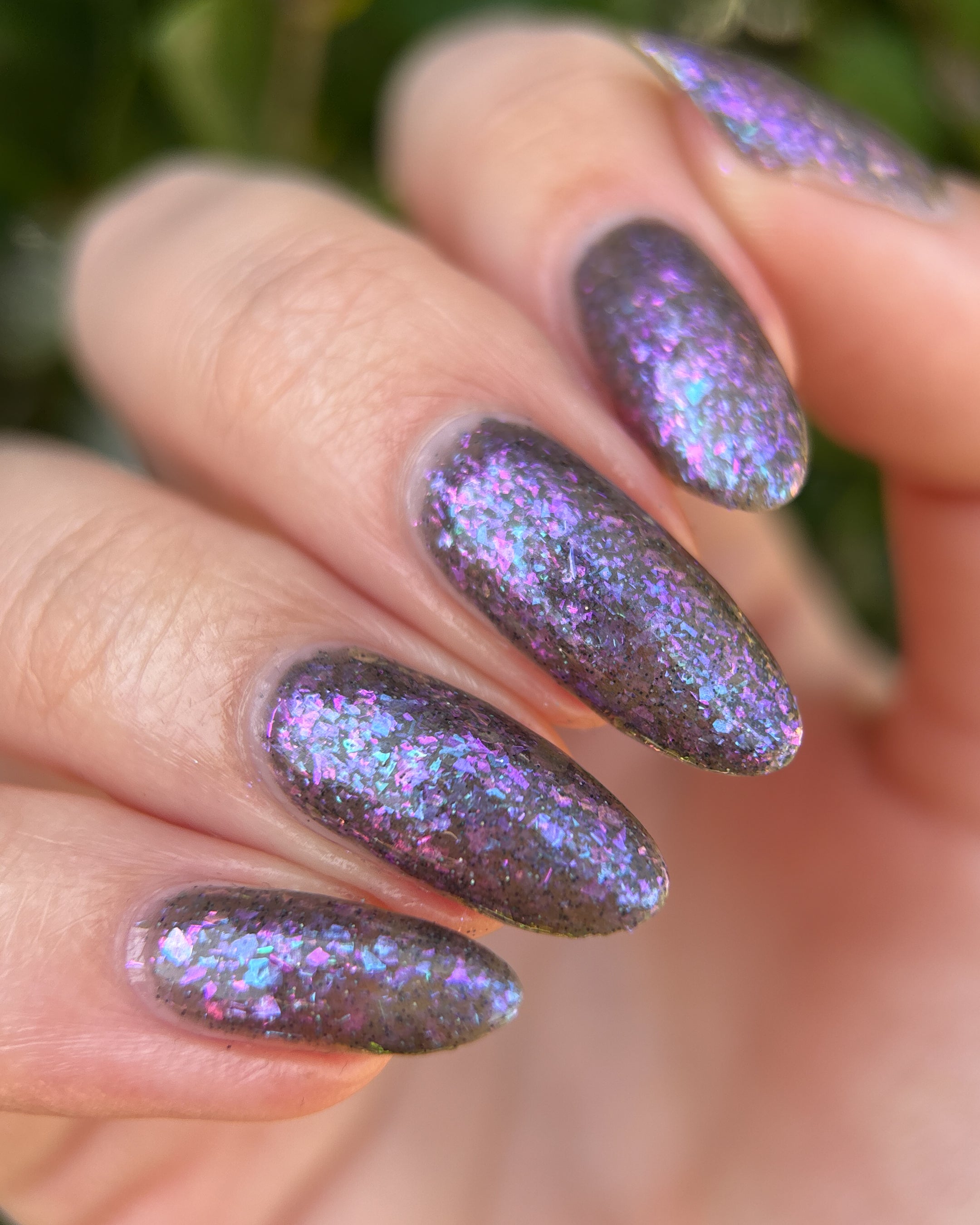 AVEN by Glitch Lacquer, soft black base, iridescent purple flakes, black holo micro-glitter, on light skin tone almond nails