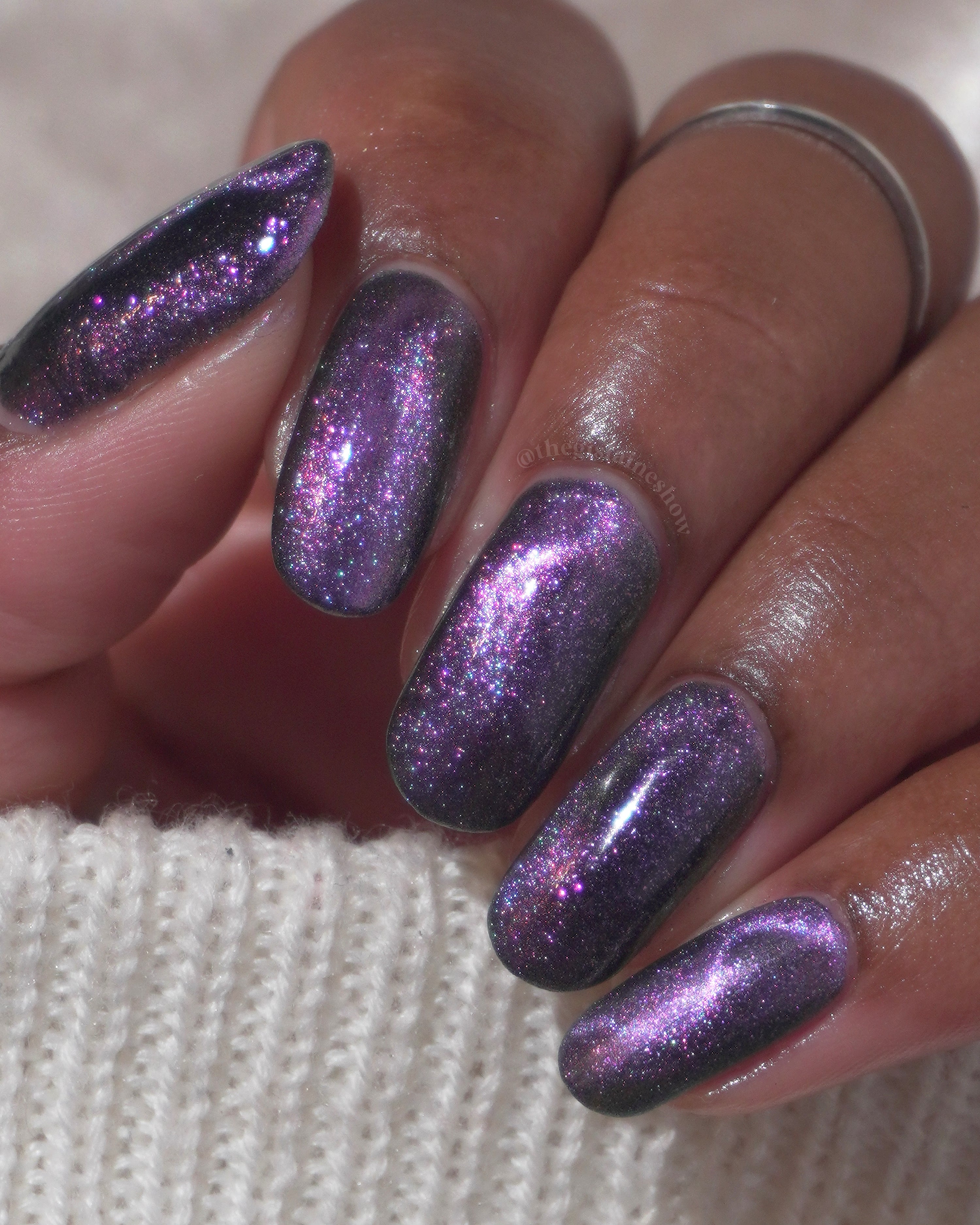 Lavender Menace by Glitch Lacquer, black jelly, purple sparkle, purple-blue magnetic, on medium-deep skin tone almond nails