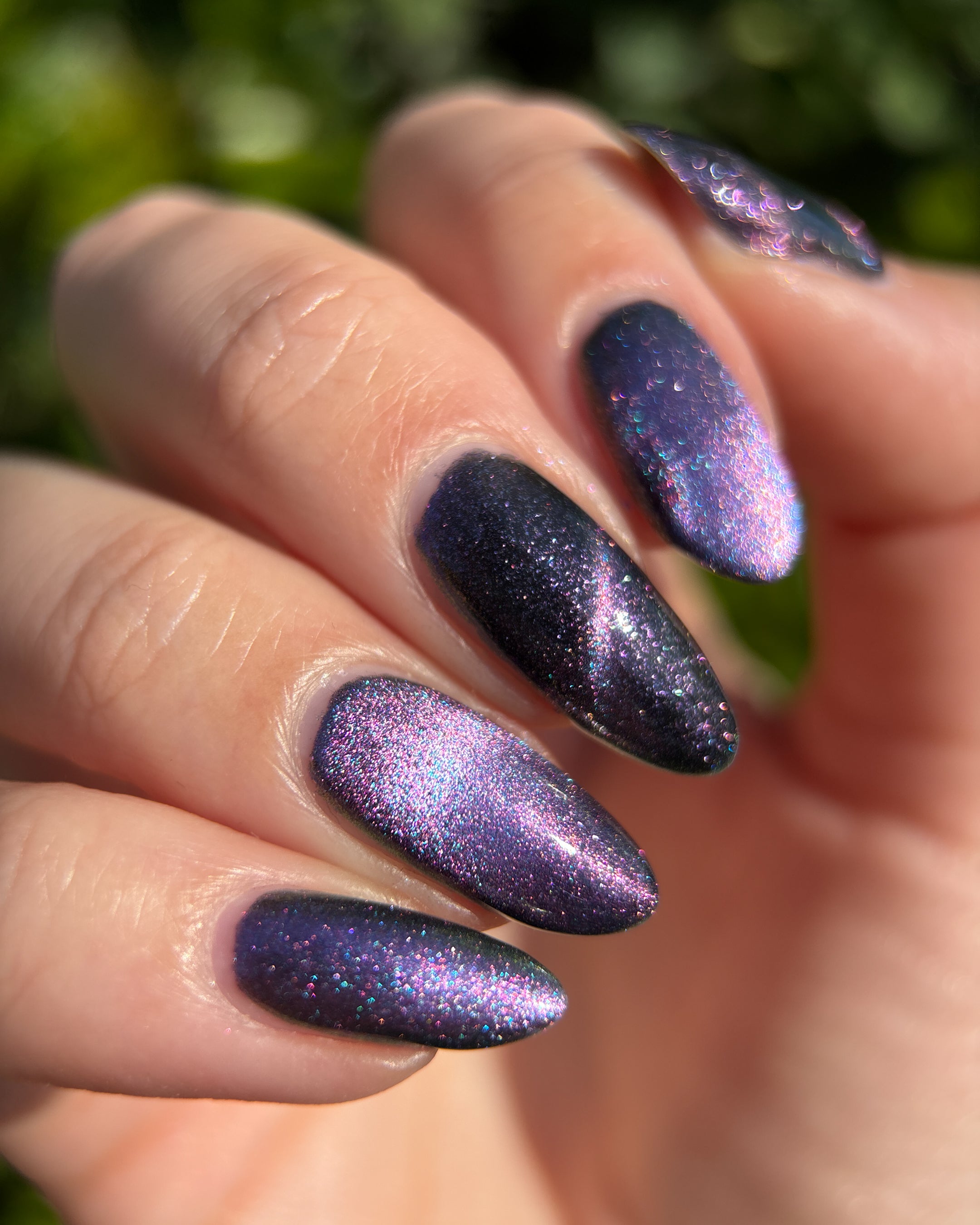 Lavender Menace by Glitch Lacquer, black jelly, purple sparkle, purple-to-blue magnetic, on light skin tone almond nails