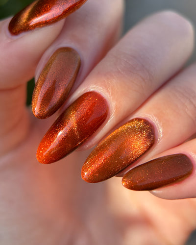 Marigold by Glitch Lacquer, burnt orange jelly, orange-to-gold magnetic cat-eye, on light skin tone almond nails