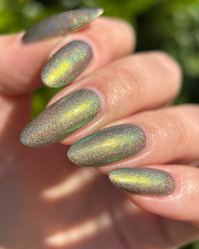 Safe House Glow by Glitch Lacquer, grey base, gold-to-teal multichrome shift, holo shimmer, on light skin tone almond nails