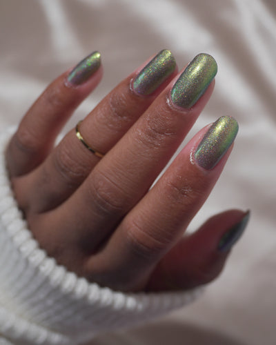 Safe House Glow by Glitch Lacquer, grey base, gold-to-teal multichrome shift, holo shimmer, on medium skin tone oval nails