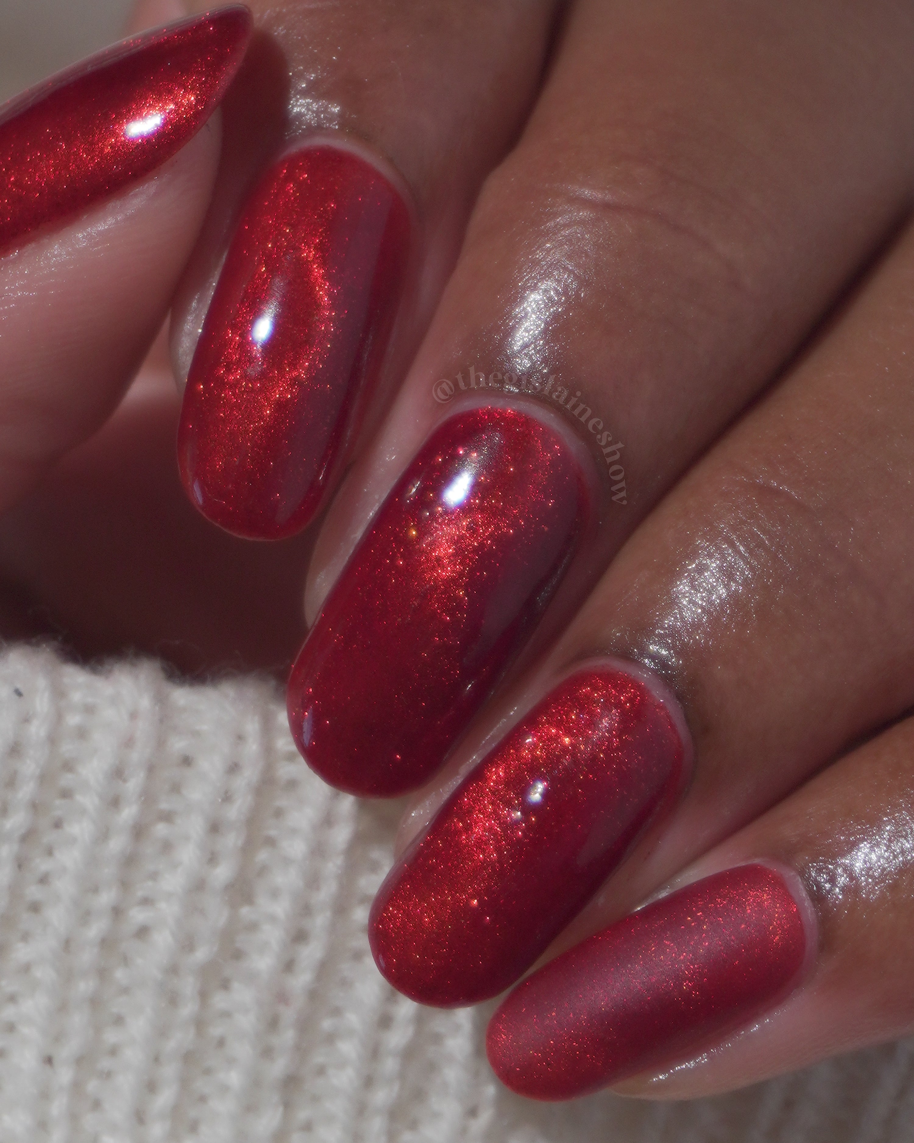 Stonewall by Glitch Lacquer, brick red jelly with crimson magnetic shimmer, on medium-deep skin tone oval nails