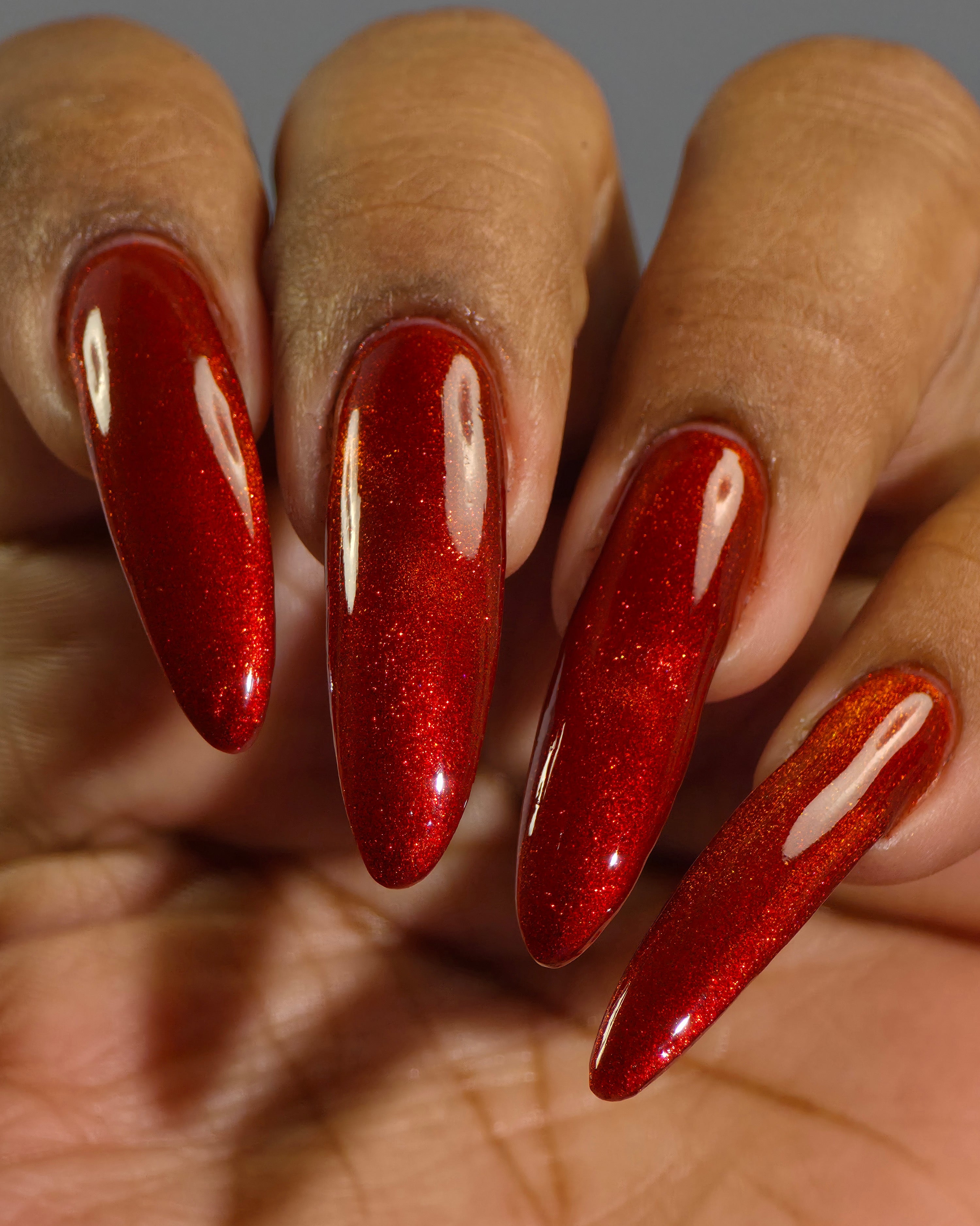 Stonewall by Glitch Lacquer, brick red jelly with red magnetic shimmer, swatched on medium-deep skin tone nails