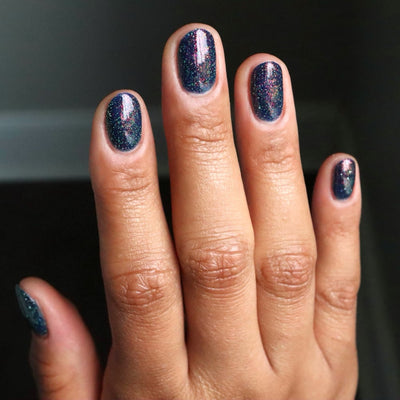 Mr Luthoooor by Danglefoot Nail Polish, blue-green multichrome reflective shimmer glitter on a medium skin tone hand