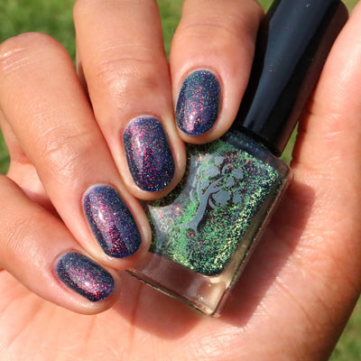 Mr Luthoooor by Danglefoot Nail Polish, blue-green multichrome reflective shimmer glitter bottle held in a light-medium hand