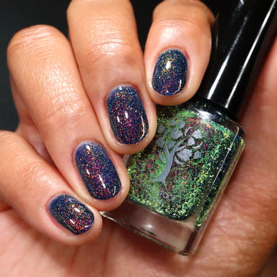 Mr Luthoooor by Danglefoot Nail Polish, blue-green multichrome reflective shimmer glitter bottle held in a light-medium hand