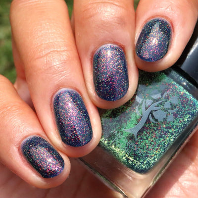Mr Luthoooor by Danglefoot Nail Polish, blue-green multichrome reflective shimmer glitter bottle held in a light-medium hand