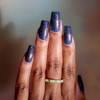 Mr Luthoooor by Danglefoot Nail Polish, blue-green multichrome reflective shimmer glitter on a medium-deep skin tone hand