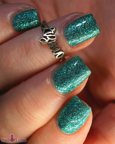 Mutant and Proud by Danglefoot Nail Polish, green-teal holographic reflective glitter flakie on a light-medium skin tone hand