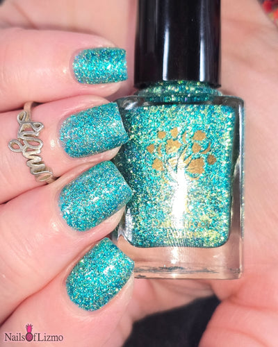 Mutant and Proud by Danglefoot Nail Polish, green-teal holographic reflective glitter flakie bottle held in a light hand