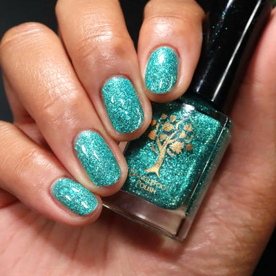 Mutant and Proud by Danglefoot Nail Polish, green-teal holographic reflective glitter flakie bottle held in a light-medium hand