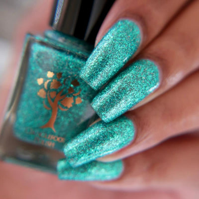 Mutant and Proud by Danglefoot Nail Polish, green-teal holographic reflective glitter flakie bottle held in a light-medium hand