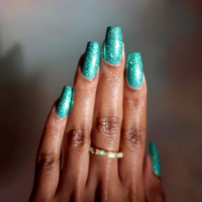 Mutant and Proud by Danglefoot Nail Polish, green-teal holographic reflective glitter flakie on a medium-deep skin tone hand