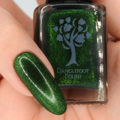 New Divide by Danglefoot Nail Polish, green shimmer jelly magnetic bottle held in a light hand