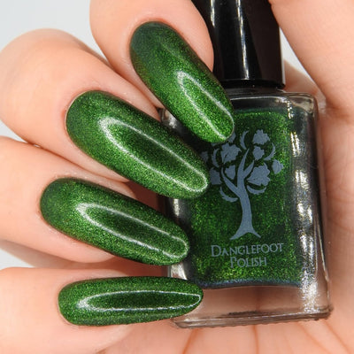 New Divide by Danglefoot Nail Polish, green shimmer jelly magnetic bottle held in a light hand