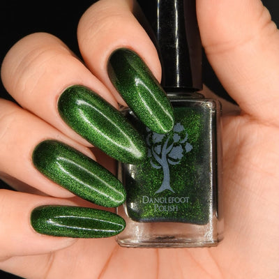 New Divide by Danglefoot Nail Polish, green shimmer jelly magnetic bottle held in a light hand