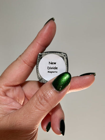 New Divide by Danglefoot Nail Polish, green shimmer jelly magnetic bottle held in a light-medium hand
