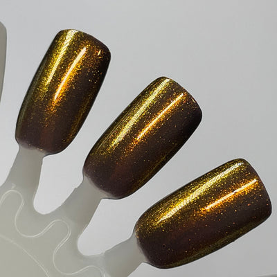 Ox by Dam Nail Polish, warm brown base with bronze-to-gold shimmer and linear light-catching streaks, swatch stick
