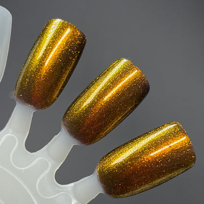 Ox by Dam Nail Polish, amber-brown base with gold-to-bronze-orange shifting shimmer, swatch stick