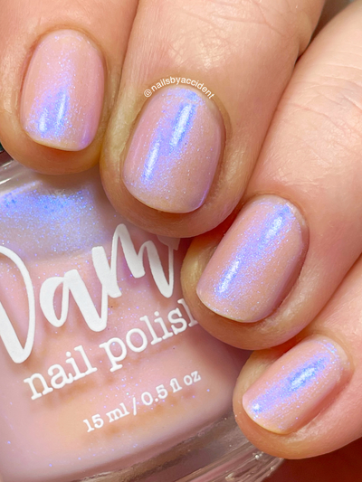 A Whimsical Dream by Dam Nail Polish, sheer blush pink base with blue-purple shimmer floating over the jelly base in bright daylight, on a light-medium skin tone hand