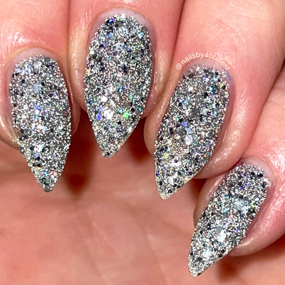 I Started the Dam Thing by Dam Nail Polish, silver micro and chunky glitter with prismatic iridescent sparks under direct flash, on a light-medium skin tone hand