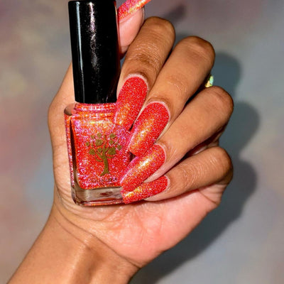 Protector of the Deep by Danglefoot Nail Polish, orange-pink reflective shimmer glitter bottle held in a medium-deep hand