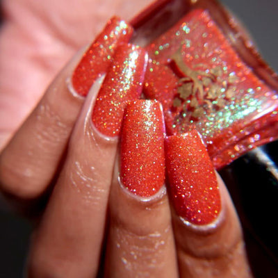 Protector of the Deep by Danglefoot Nail Polish, orange-pink reflective shimmer glitter on a medium skin tone hand
