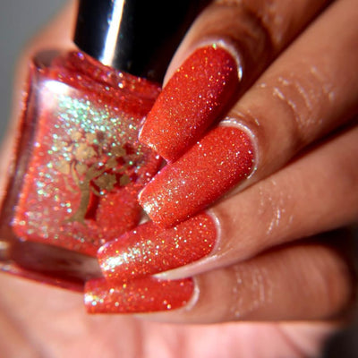 Protector of the Deep by Danglefoot Nail Polish, orange-pink reflective shimmer glitter bottle held in a light-medium hand