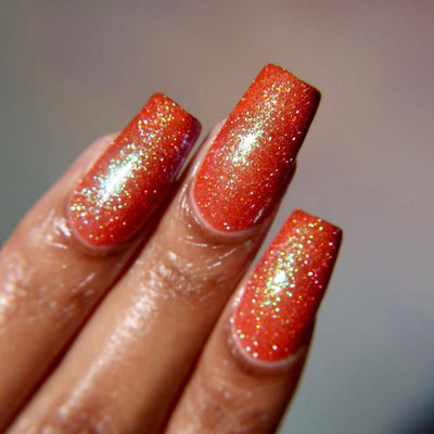 Protector of the Deep by Danglefoot Nail Polish, orange-pink reflective shimmer glitter on a light-medium skin tone hand