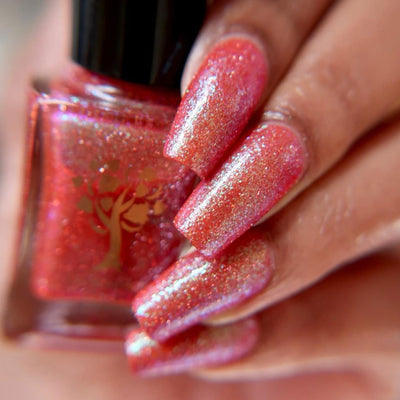 Protector of the Deep by Danglefoot Nail Polish, orange-pink reflective shimmer glitter bottle held in a light-medium hand