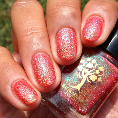 Protector of the Deep by Danglefoot Nail Polish, orange-pink reflective shimmer glitter on a light-medium skin tone hand