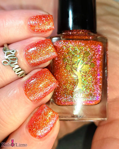 Protector of the Deep by Danglefoot Nail Polish, orange-pink reflective shimmer glitter bottle held in a light hand