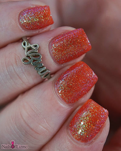 Protector of the Deep by Danglefoot Nail Polish, orange-pink reflective shimmer glitter on a light skin tone hand