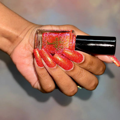 Protector of the Deep by Danglefoot Nail Polish, orange-pink reflective shimmer glitter bottle held in a medium-deep hand