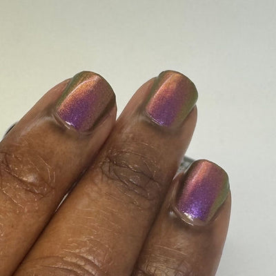 Thorn by 'Ard As Nails, multichrome chrome shifting from magenta-purple to burnt orange-red to olive gold across the nail, on a deep skin tone hand