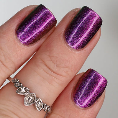 Thorn by 'Ard As Nails, magenta-purple multichrome with dramatic linear magnetic pattern showing deep near-black shadow zones, on a light skin tone hand