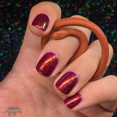 Should I Stay by Dam Nail Polish, deep fuchsia jelly with gold-to-green-to-blue multichrome shimmer flakies under direct flash, on a light skin tone hand