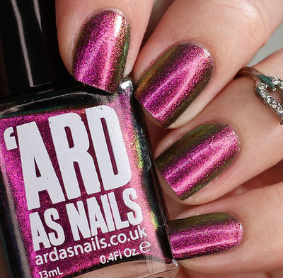 Joyeau by 'Ard As Nails, gold-pink multichrome chrome with streak-pattern shift from vivid magenta-pink to olive-gold, bottle held in a light skin tone hand