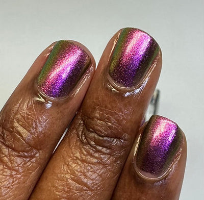 Joyeau by 'Ard As Nails, gold-pink multichrome chrome shifting vivid magenta-pink to olive-gold with deep violet in shadow zones, on a deep skin tone hand