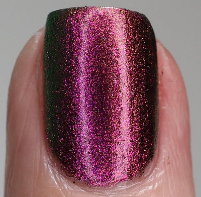 Joyeau by 'Ard As Nails, gold-pink multichrome chrome showing intense magenta-pink to deep burgundy-red with forest green shadow shift under direct flash, on a light skin tone hand