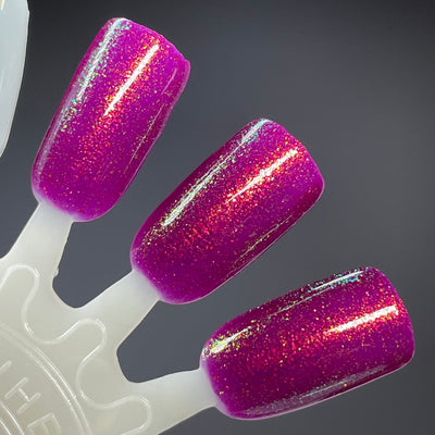 Should I Stay by Dam Nail Polish, deep fuchsia jelly with gold, green, and teal multichrome shimmer flashing red and teal under studio light, swatch stick