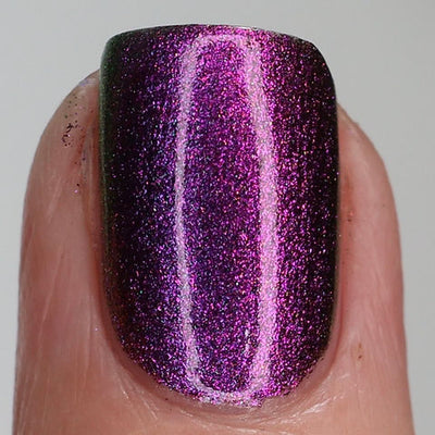 Thorn by 'Ard As Nails, intense magenta-purple chrome with bright pink highlight streak and deep shadowed edges under direct flash, on a light-medium skin tone hand