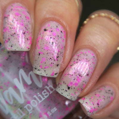 Shimmer Storm by Dam Nail Polish, sheer white base with neon hot pink glitter chunks, black glitter flecks, and a soft pink shimmer glow, on a light-medium skin tone hand