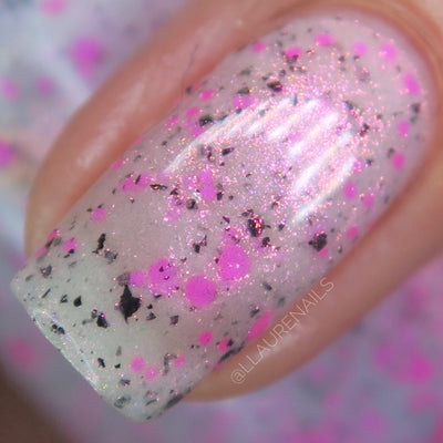 Shimmer Storm by Dam Nail Polish, macro close-up of neon magenta-pink dot glitters, irregular black glitter flakes, and pink-to-gold microshimmer over a soft white base