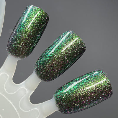 Snake by Dam Nail Polish, black jelly with bright green-to-teal multichrome shift and purple reflective glitter, swatch stick