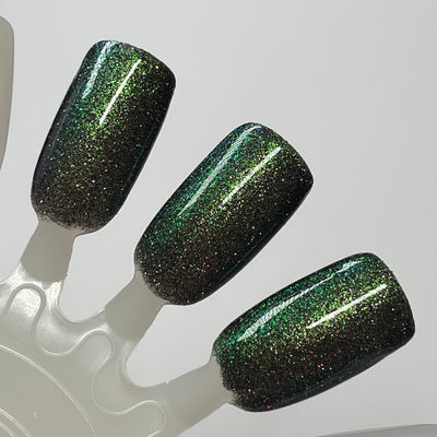 Snake by Dam Nail Polish, black jelly with green-to-teal multichrome shift and scattered purple reflective glitter, swatch stick